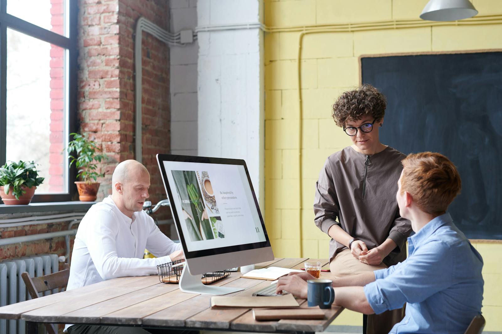 Three adults collaborating in a modern workspace during a brainstorming session.